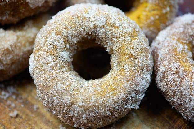 A close up of a sugar doughnut on a cutting board.