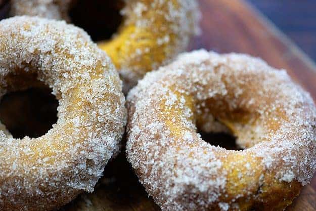 A close up of a few doughnuts on a cutting board.