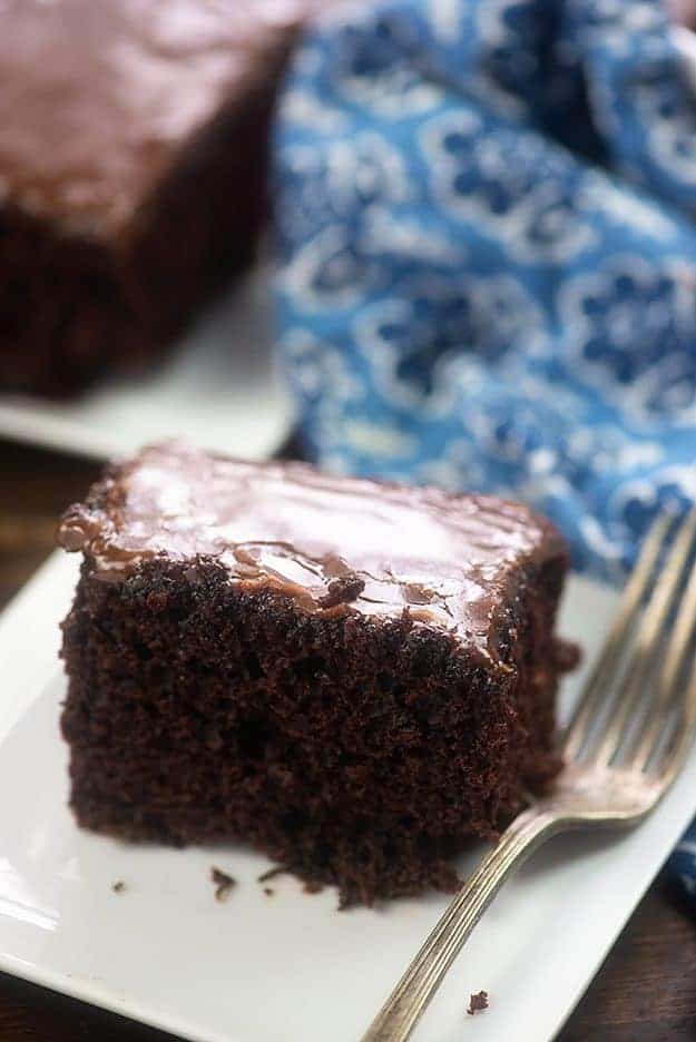 A piece of chocolate cake on a plate, with a fork.