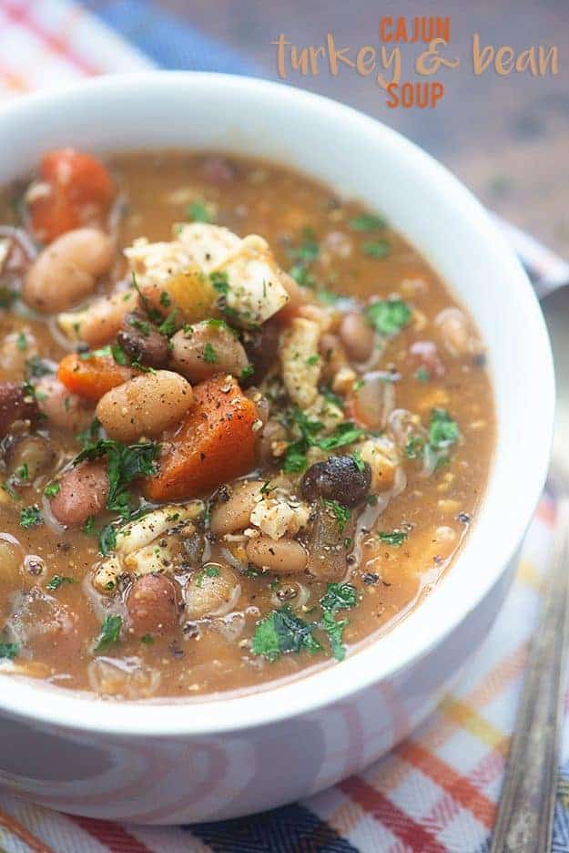 A bowl of soup with beans, turkey, and carrots.