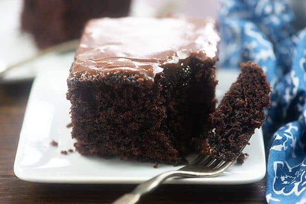 A piece of chocolate cake on a plate with a bite taken out of it.