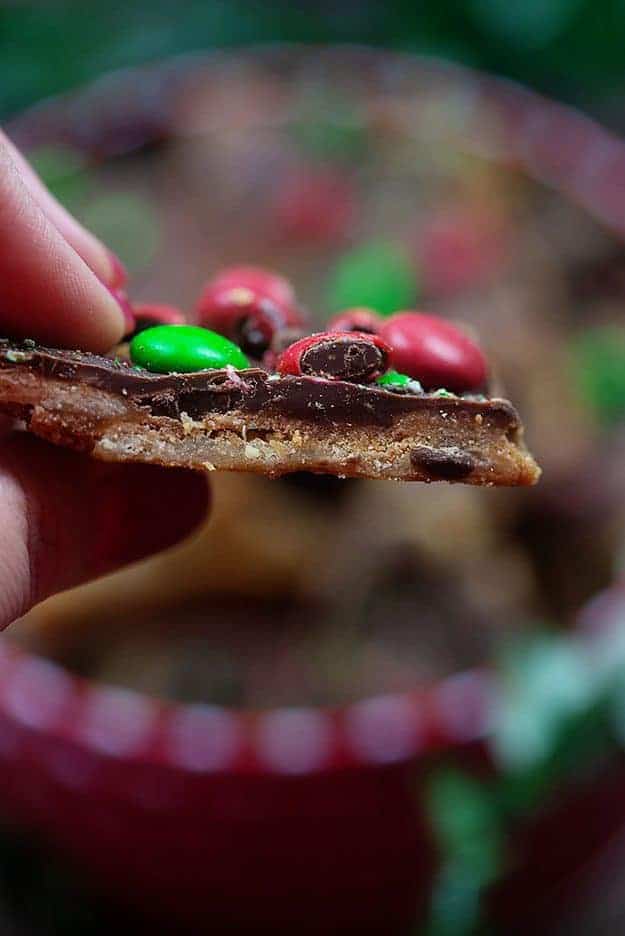 A close up of a woman holding a piece of toffee.