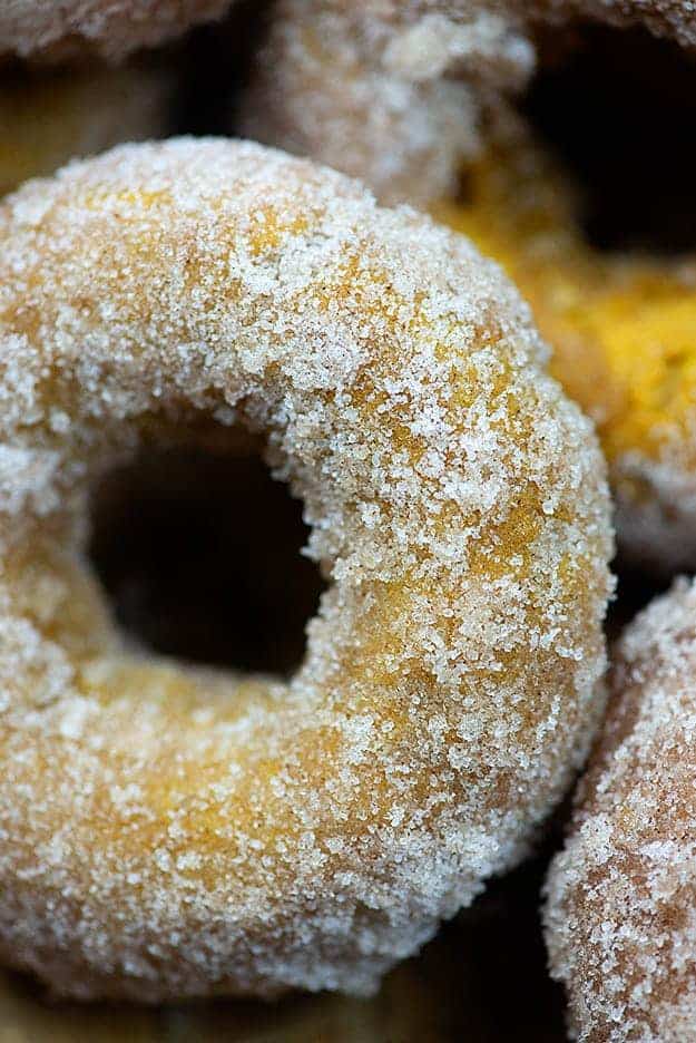 Close up of a sugar donut leaned against other donuts.