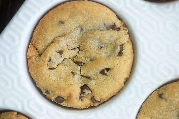 A closeup of a chocolate chip cookie in a muffin pan.