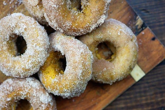 A half dozen sugar donut on a cutting board.