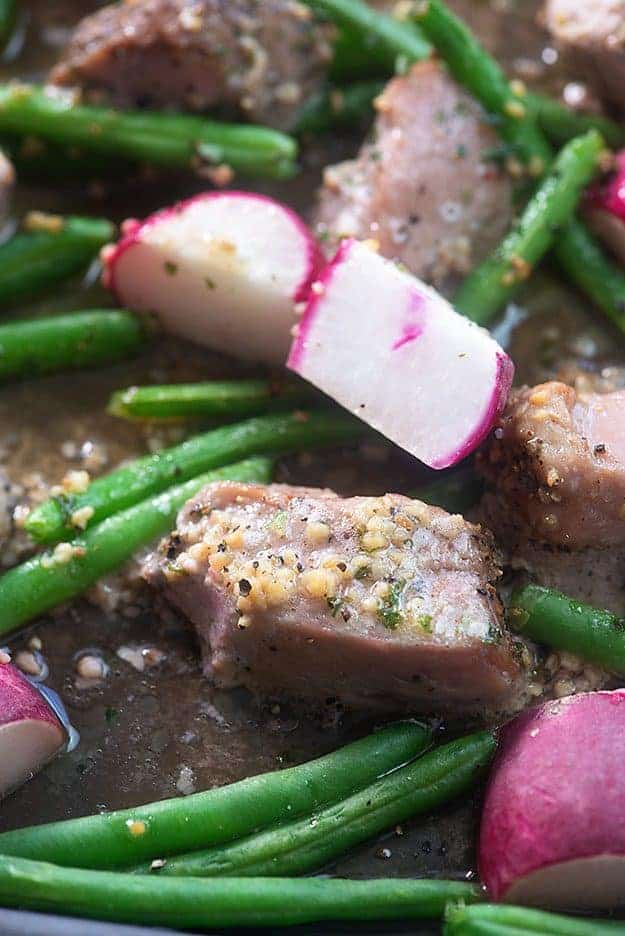 A close up of pork, radishes, and green beans.