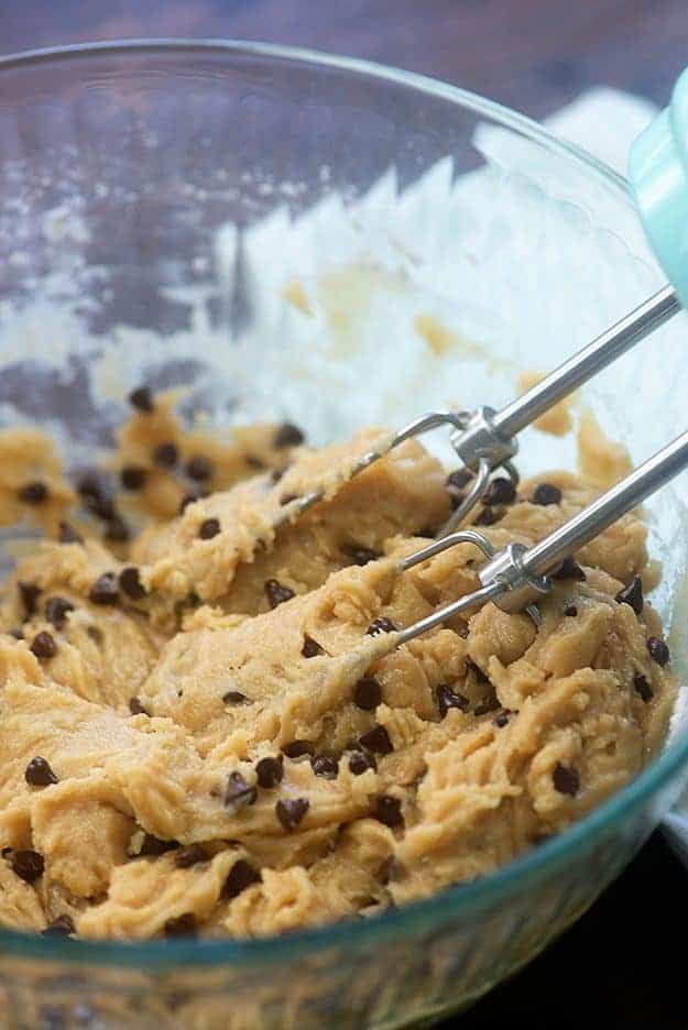 chocolate chip cookie dough in a glass bowl being mixed.