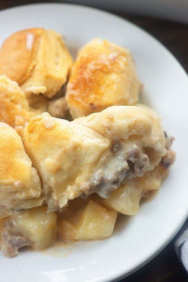 Close up of biscuit and gravy casserole in a white bowl.