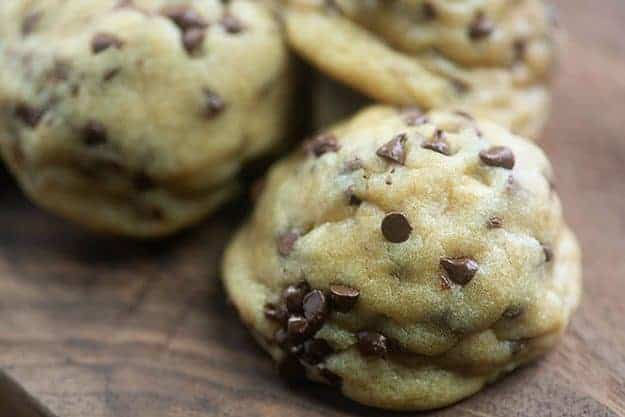 A few chocolate chip cookies on a wooden table.