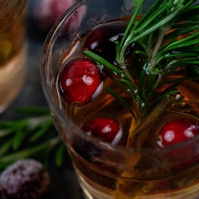 Close up of a glass of sangria with cherries floating on top.