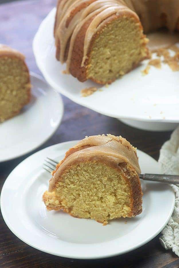 Piece of pound cake and a fork on a small white plate.