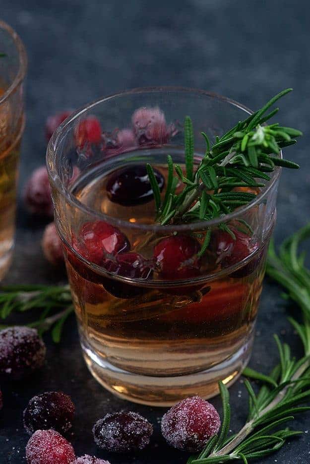 A glass of sangria on a table with rosemary.