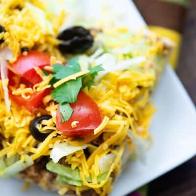 A slice of taco pizza on a square plate.