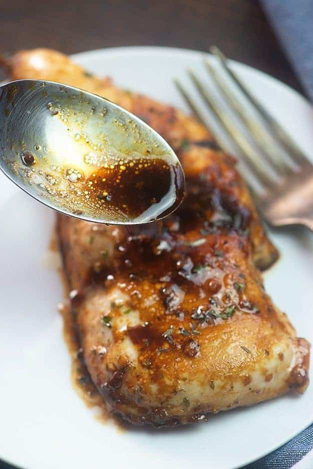 Using a spoon to drizzle balsamic dressing on top of chicken.