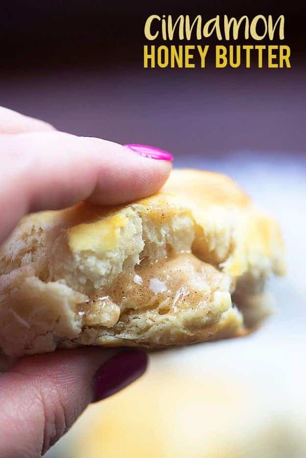 A woman holding a biscuit topped with cinnamon honey butter 