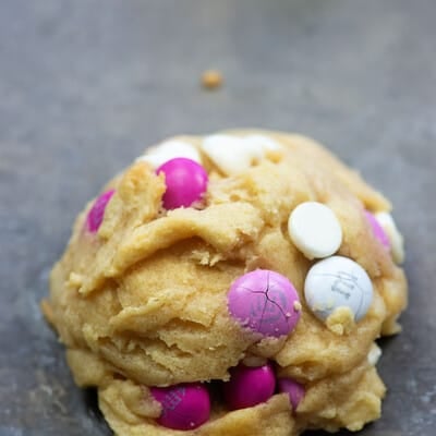 A close up of white chocolate chip cookie with Valentine M&M's.