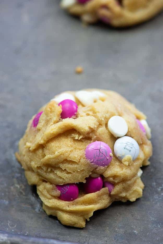 A close up of white chocolate chip cookie with Valentine M&M's.