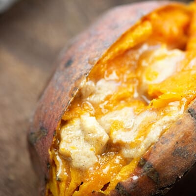 A close up of food, with Sweet potato with melted butter in the middle.