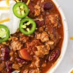 A bowl of chili next to a pot.