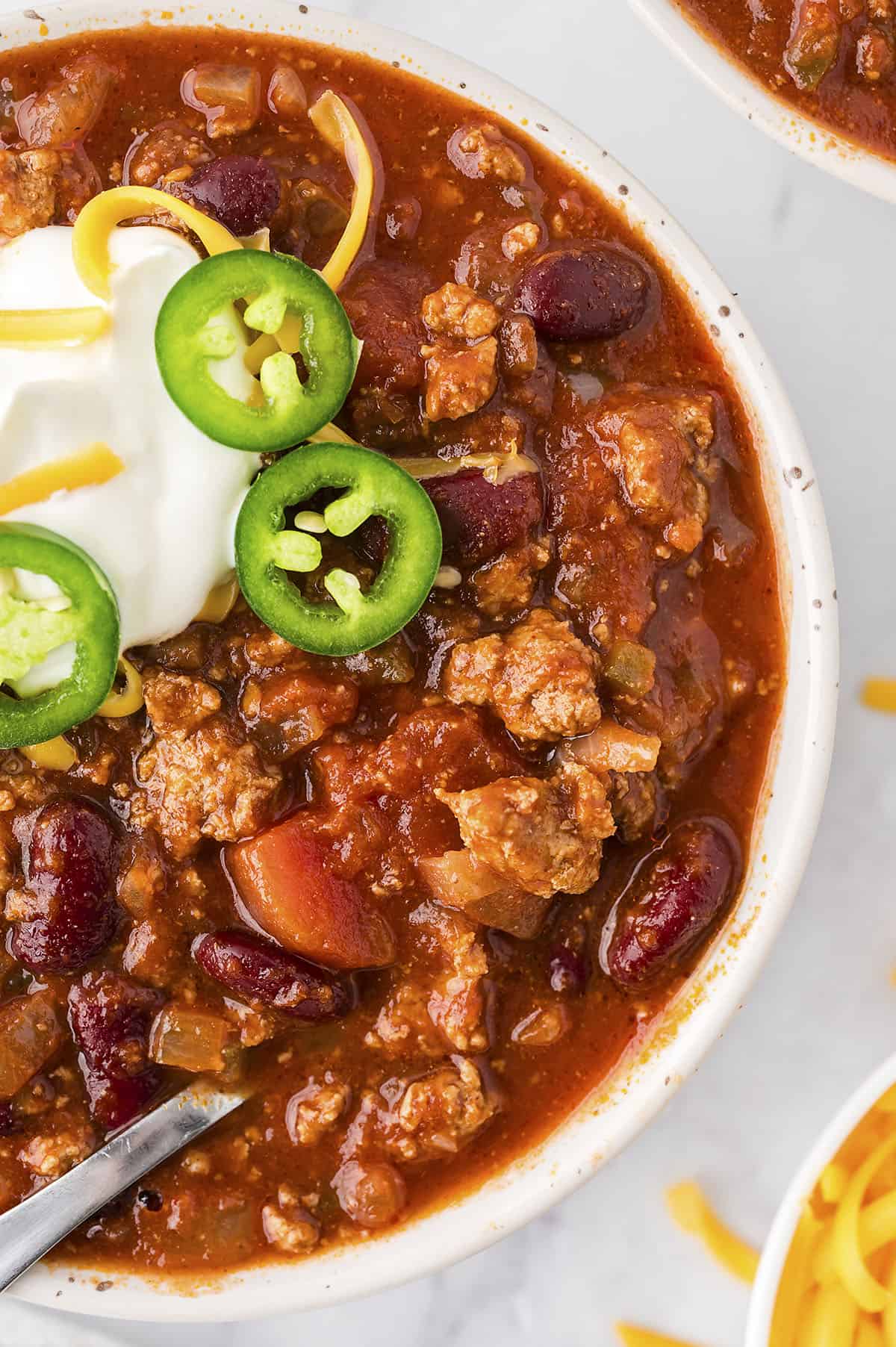 A bowl of chili next to a pot.