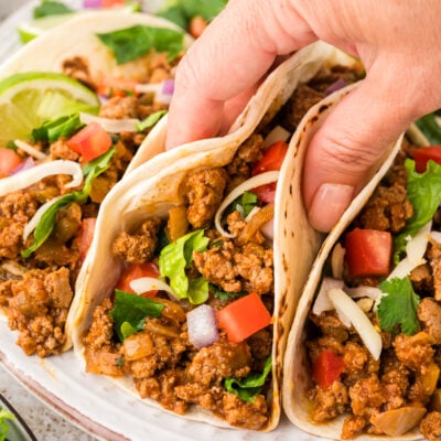 Ground turkey tacos in soft flour tortillas on plate.