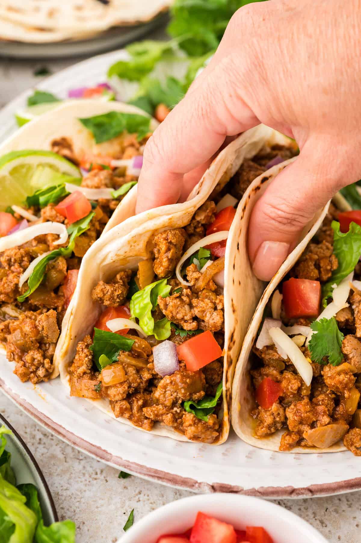 Ground turkey tacos in soft flour tortillas on plate.