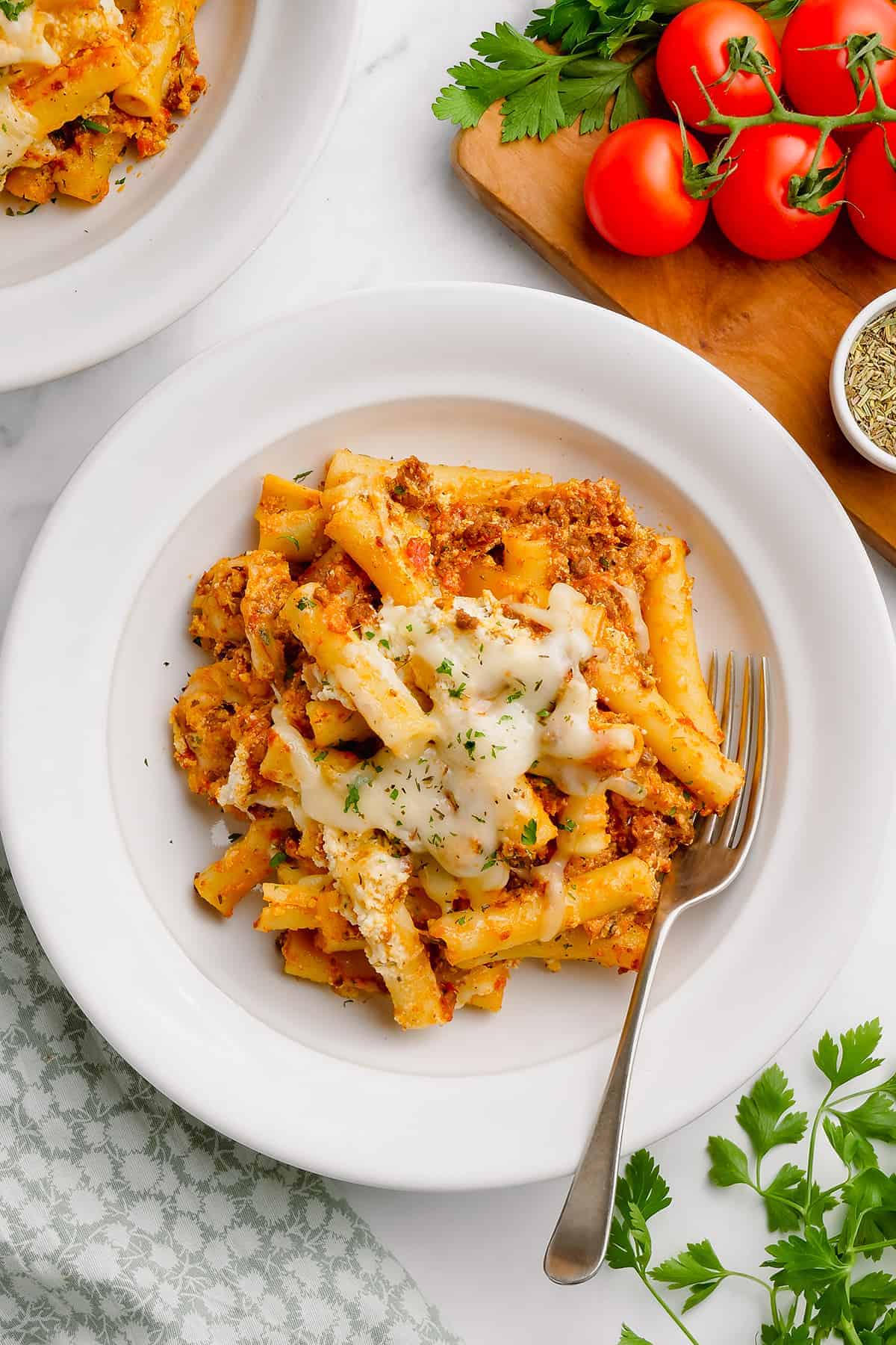 over head view of cheesy baked ziti on white plate.