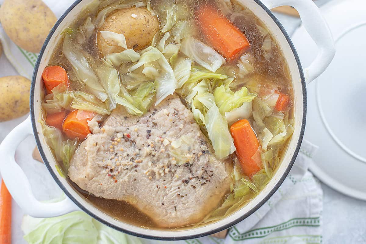 overhead view of corned beef in dutch oven with cabbage and carrots.