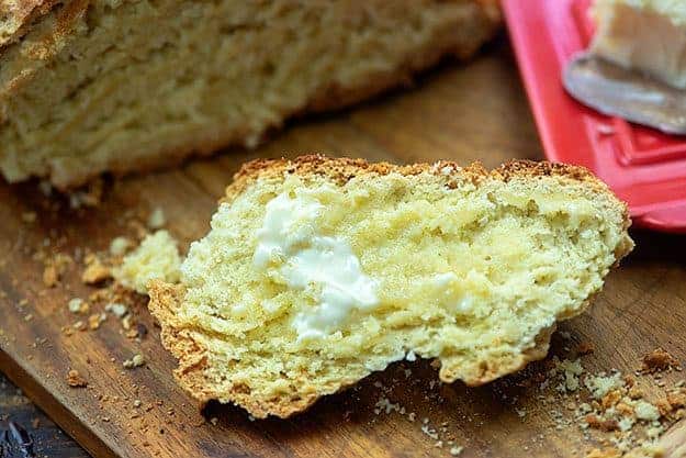A slice of bread that has been buttered on a cutting board.