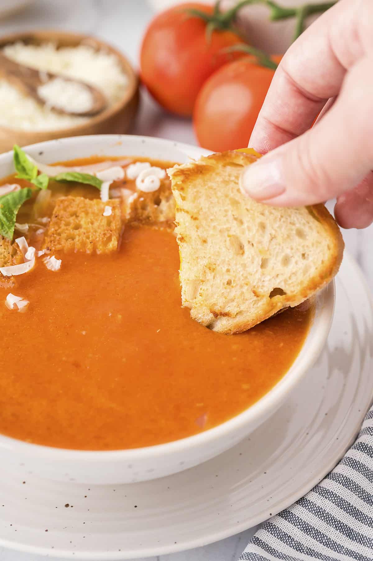 Grilled cheese being dunked in a bowl of homemade tomato soup.