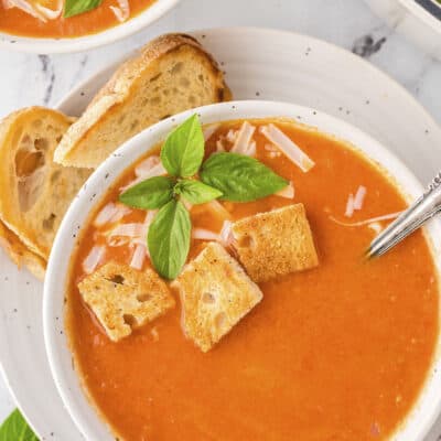 Bowl of tomato soup topped with croutons and basil.