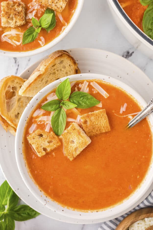 Bowl of tomato soup topped with croutons and basil.