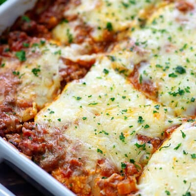 Lasagna cut into squares in a white baking dish.