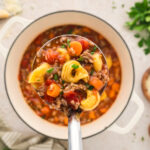 Ladle full of sausage tortellini soup.