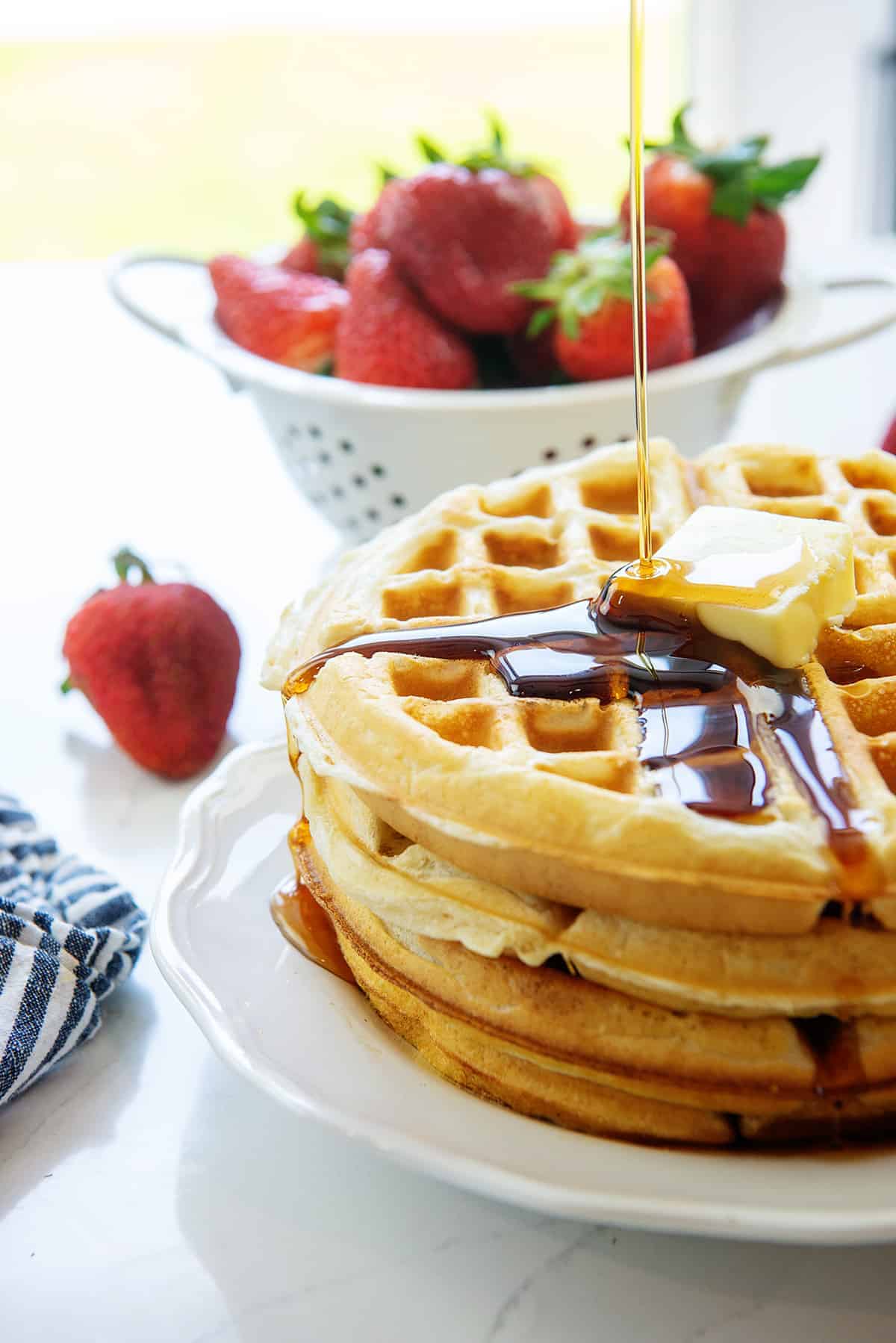 stack of Belgian waffles on white plate.