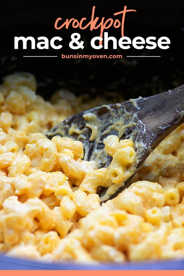 cheesy macaroni and cheese in slow cooker on wooden spoon.