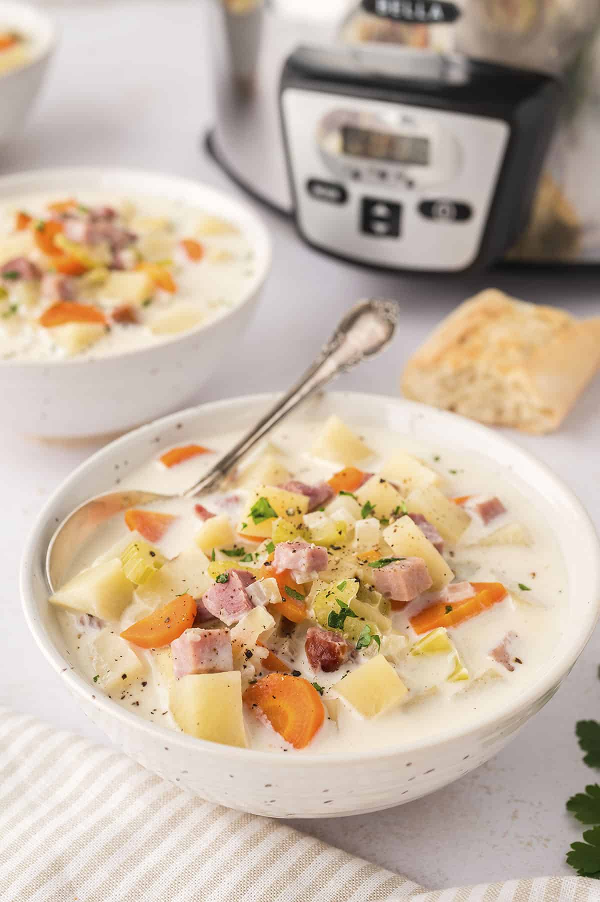 White bowl filled with crockpot ham and potato soup.