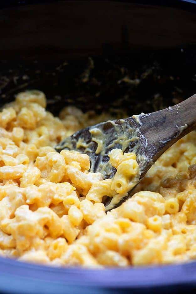 A wooden spoon dipping into macaroni and cheese.