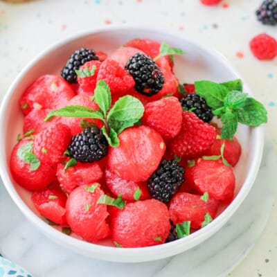 A white bowl of watermelon and raspberries.