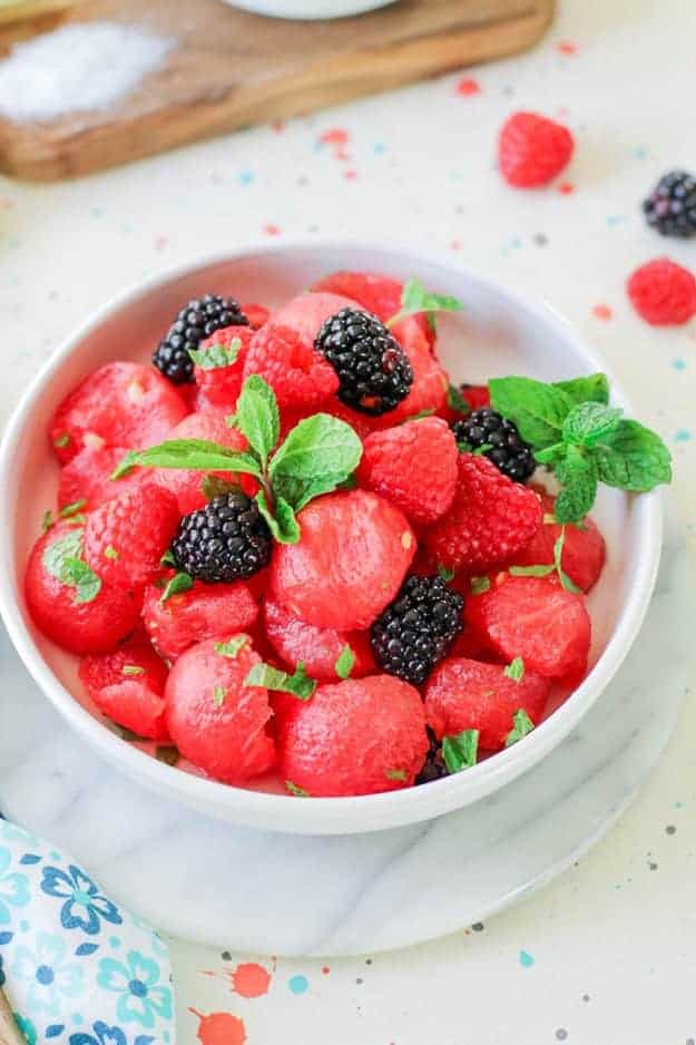 A white bowl of watermelon and raspberries.