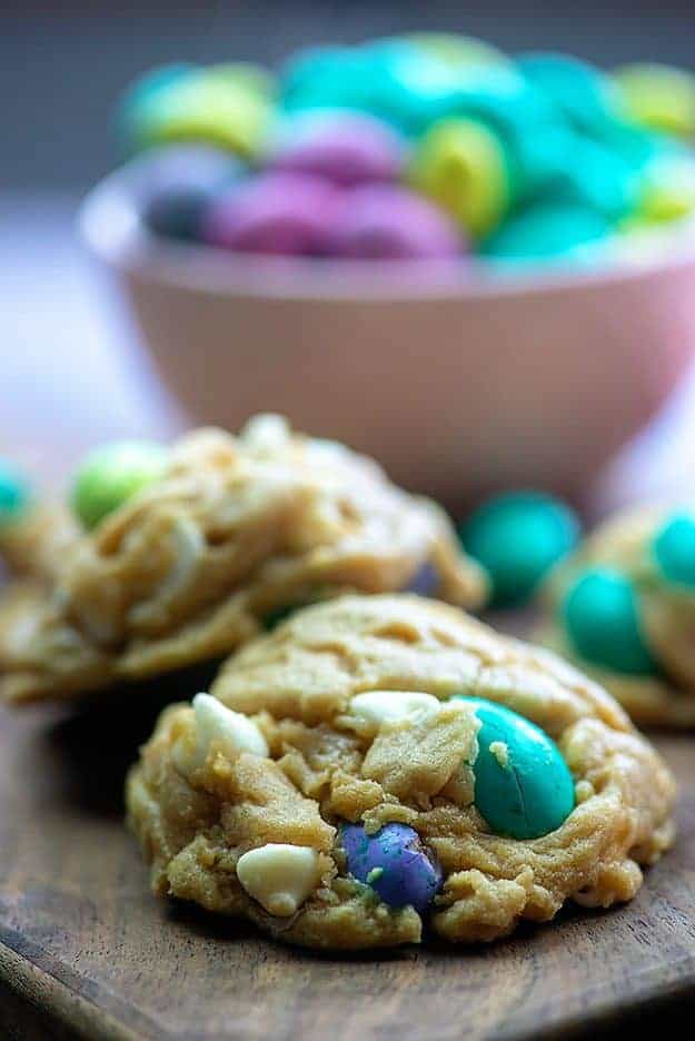 A close up of two cookies on in front of a bowl of easter egg candies.