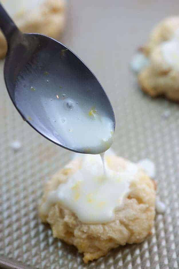 lemon glaze drizzled over lemon cookies on sheet pan