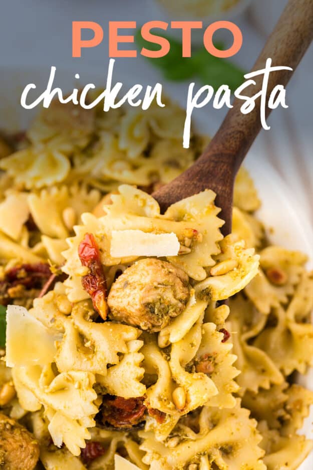 Wooden spoon in bowl of chicken pesto pasta.