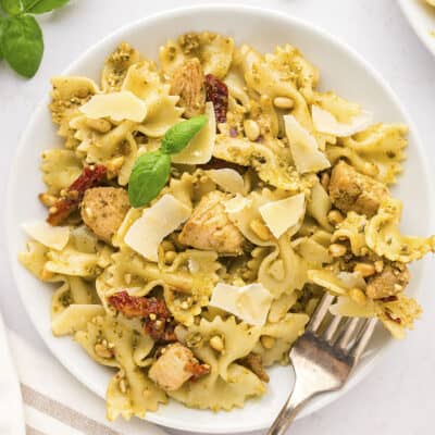 Pesto and chicken pasta on white plate with a fork.