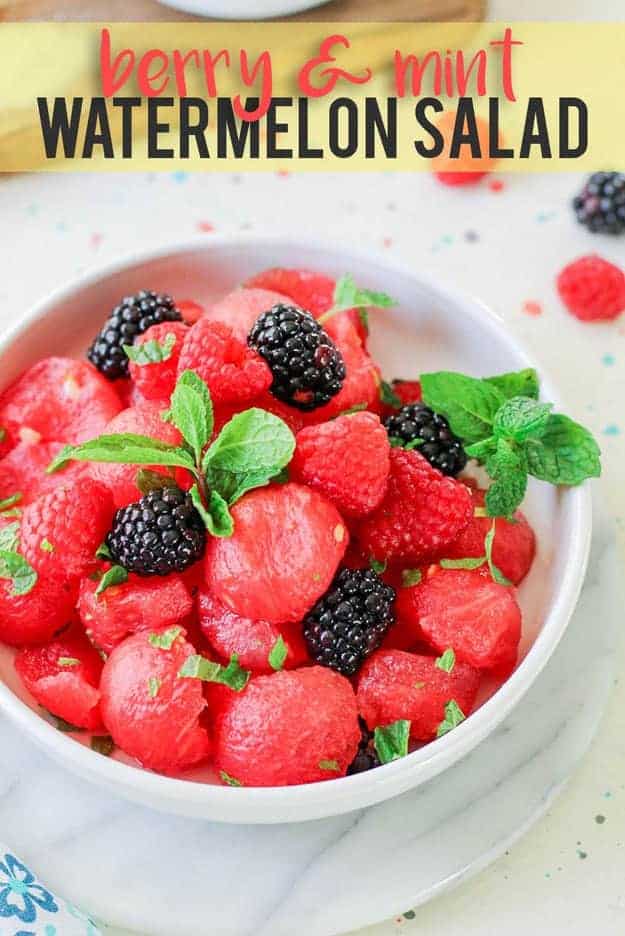 A close up of a bowl filled with watermelon scoops and raspberries.