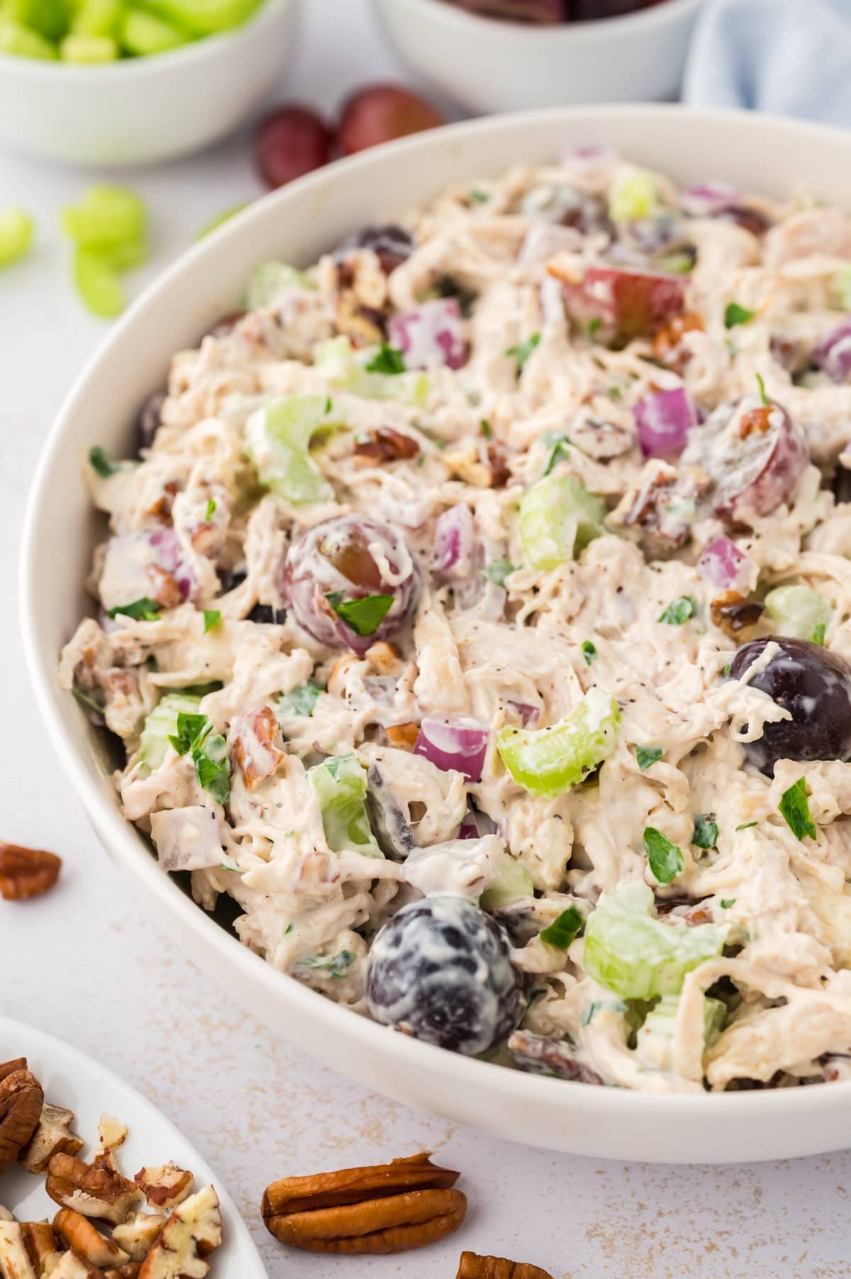 Serving dish full of chicken salad with grapes, celery, and pecans.