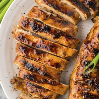 Grilled teriyaki chicken sliced on white plate,