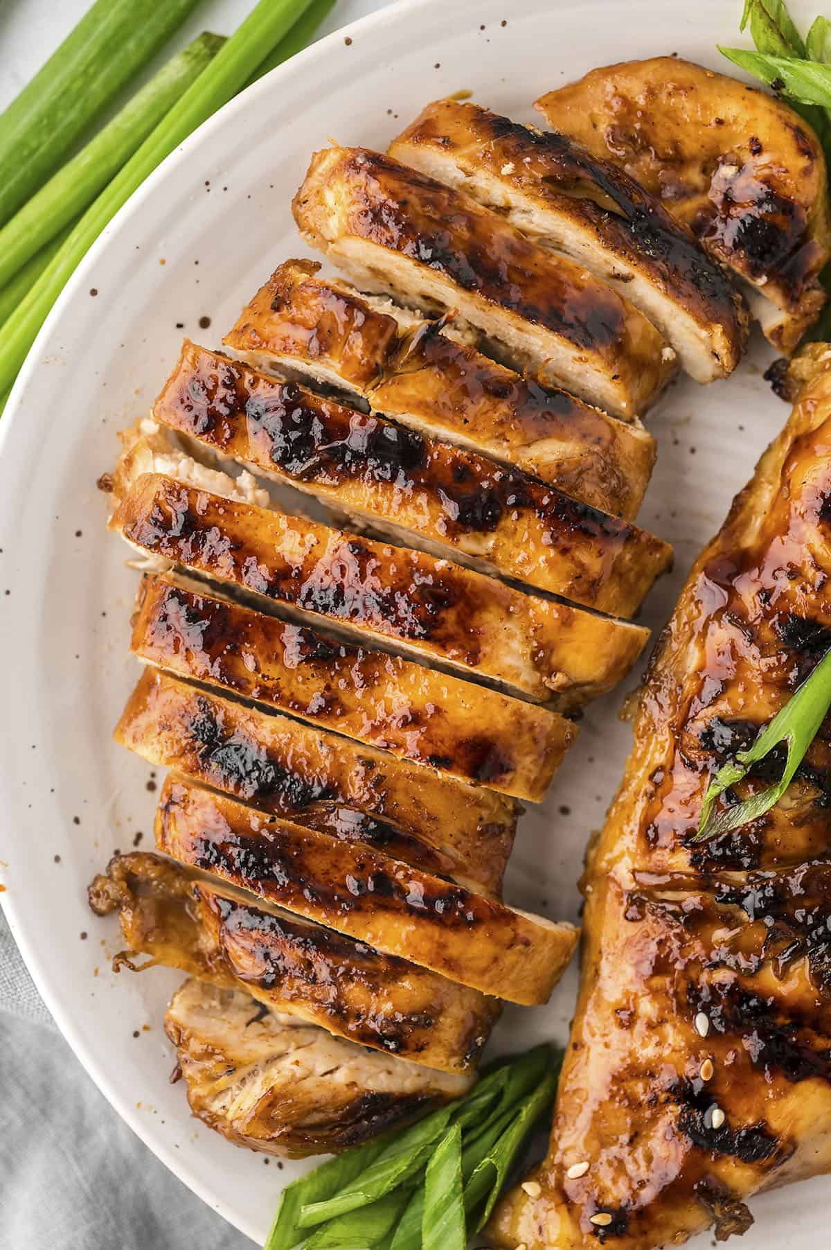 Grilled teriyaki chicken sliced on white plate,