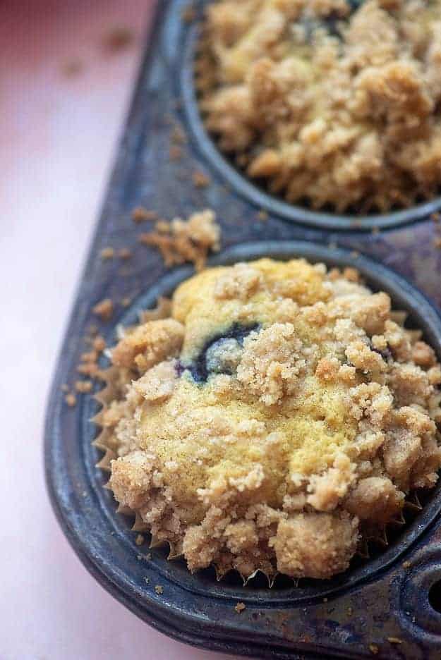 Blueberry muffin in the corner of a muffin pan.