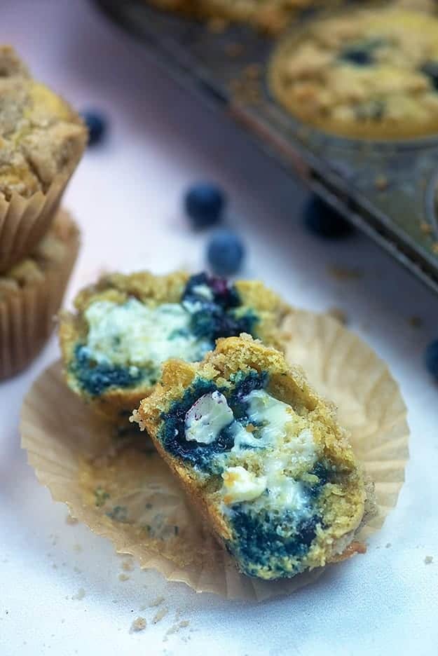 Blueberry muffin unwrapped and split in half topped with melted butter.